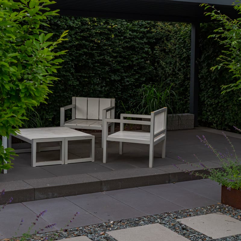 A modern patio under a pergola with a living green wall and white chairs (after)