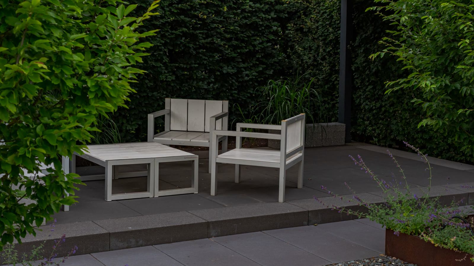 A modern patio under a pergola with a living green wall and white chairs (after)