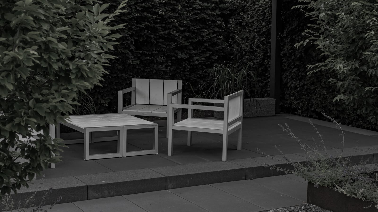 A modern patio under a pergola with a living green wall and white chairs (before, muted)