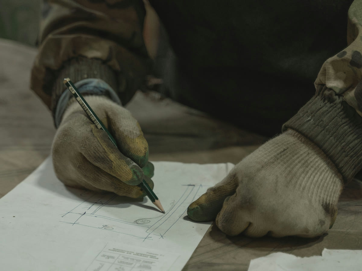 Gloved hands drawing a landscaping plan in pencil on paper